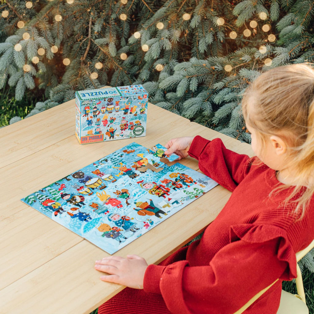 Child playing with a puzzle in front of a Christmas tree with lights.